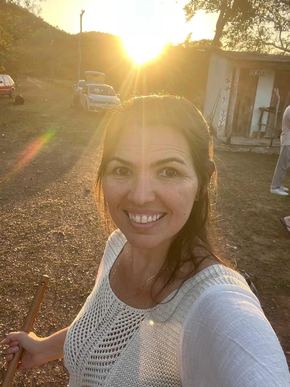 Elicéia Trindade sorrindo ao pôr do sol, com luz dourada ao fundo