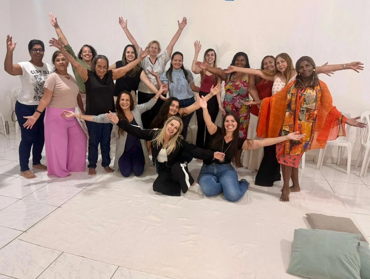Grupo grande de participantes da Constelação Familiar com os braços abertos, celebrando